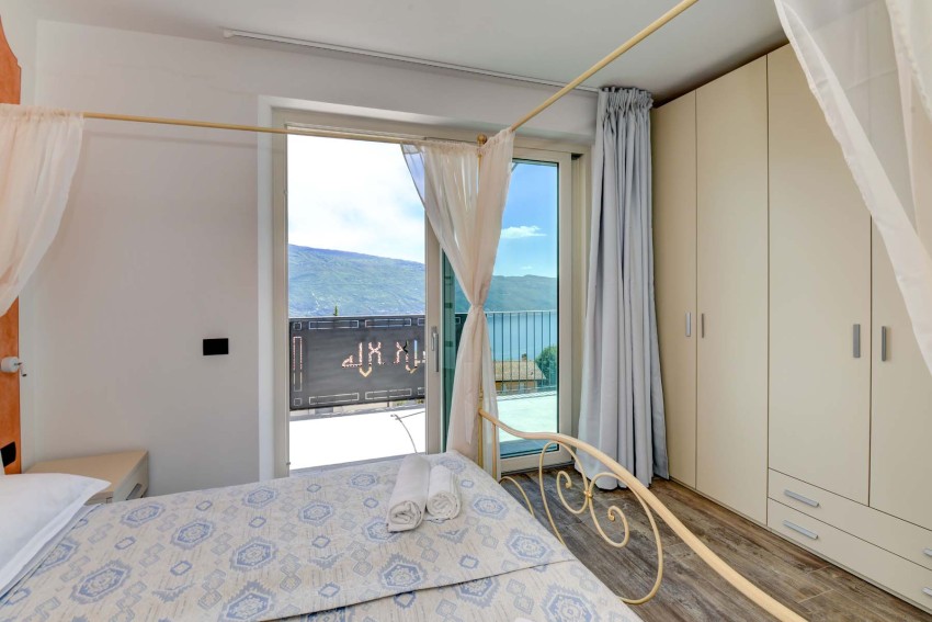 Bright bedroom with canopy bed and balcony overlooking Lake Garda
