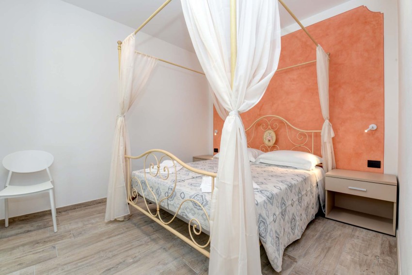 Cozy canopy bed room with coral accent wall by Lake Garda