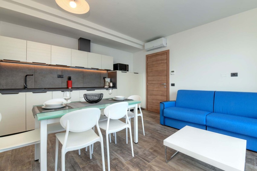 Cucina moderna con tavolo apparecchiato e divano blu, al Lago di Garda.