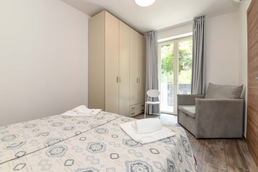 Helles Zweibettzimmer mit Schrank, Sofa und Balkon am Lago di Garda