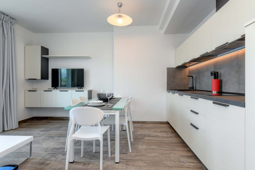 Modern kitchen-living area with set dining table and TV, near Lago di Garda
