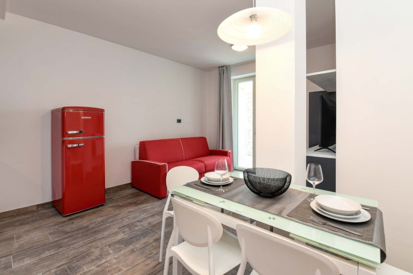 Modern living-dining area with red retro fridge and set table, Lago di Garda
