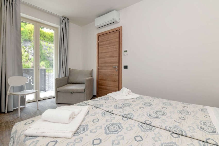 Modernes Hotelzimmer mit Bett, Handtüchern und Balkontür, Lago di Garda.