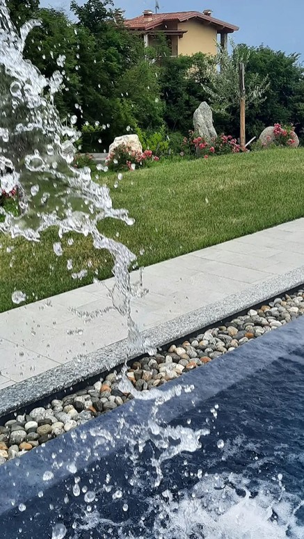 Pool fountain splash in landscaped garden by a villa, near Lake Garda.